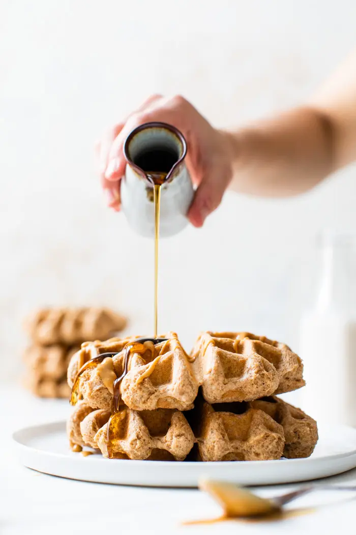 stack of waffles with syrup being poured overtop