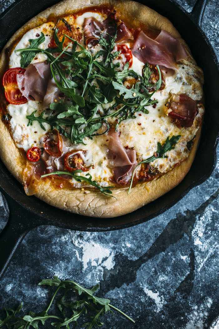 A skillet pizza with an extra thick crust topped with fresh mozzarella, prosciutto and arugula | thealmondeater.com