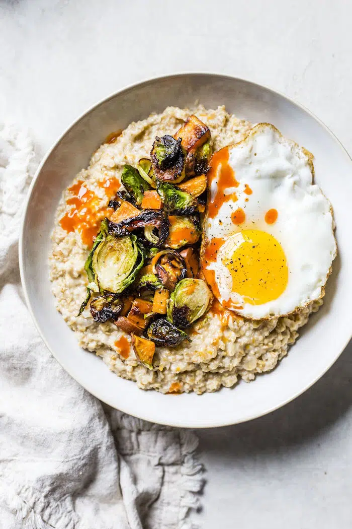 oatmeal topped with brussels sprouts, sweet potato and a fried egg