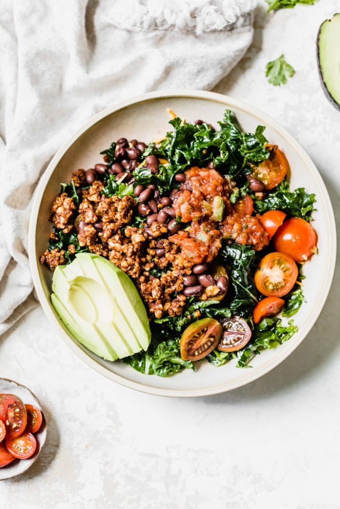 Kale salad topped with avocado, tomatoes and black beans
