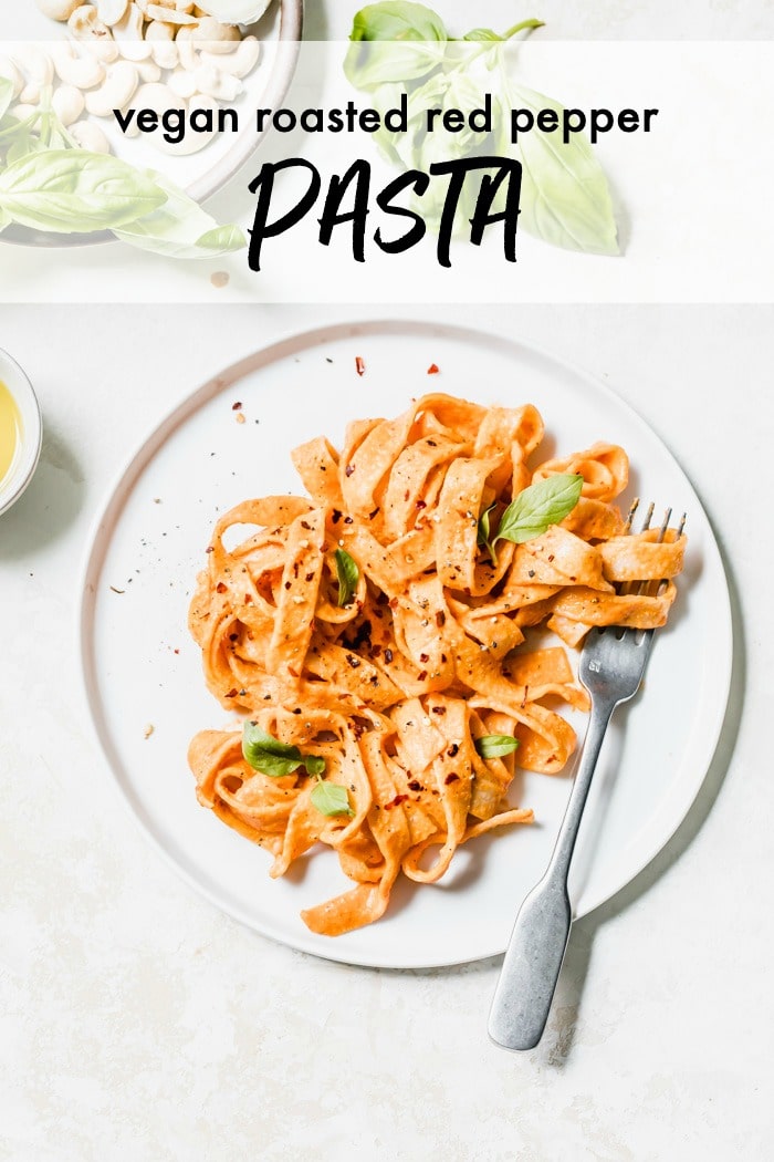 A plate of pasta with roasted red pepper sauce and basil as a garnish