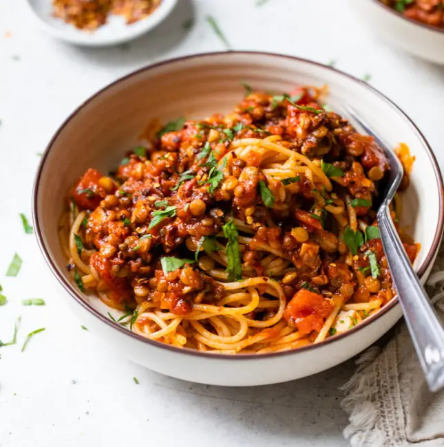a bowl of pasta with lentils and red sauce