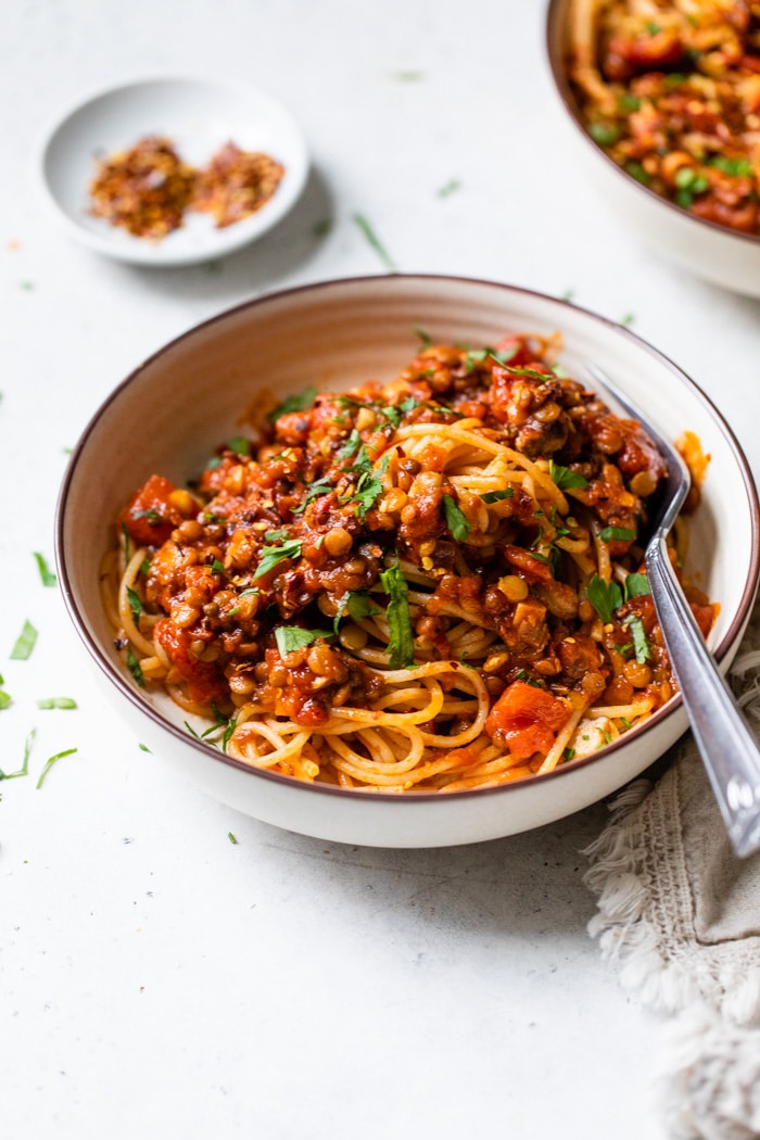 a bowl of pasta with lentils and red sauce