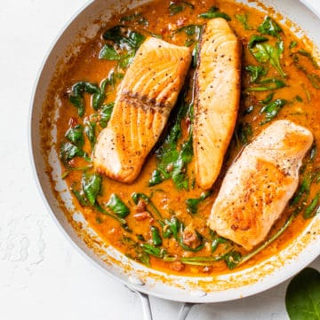salmon in a skillet with sun-dried tomato sauce