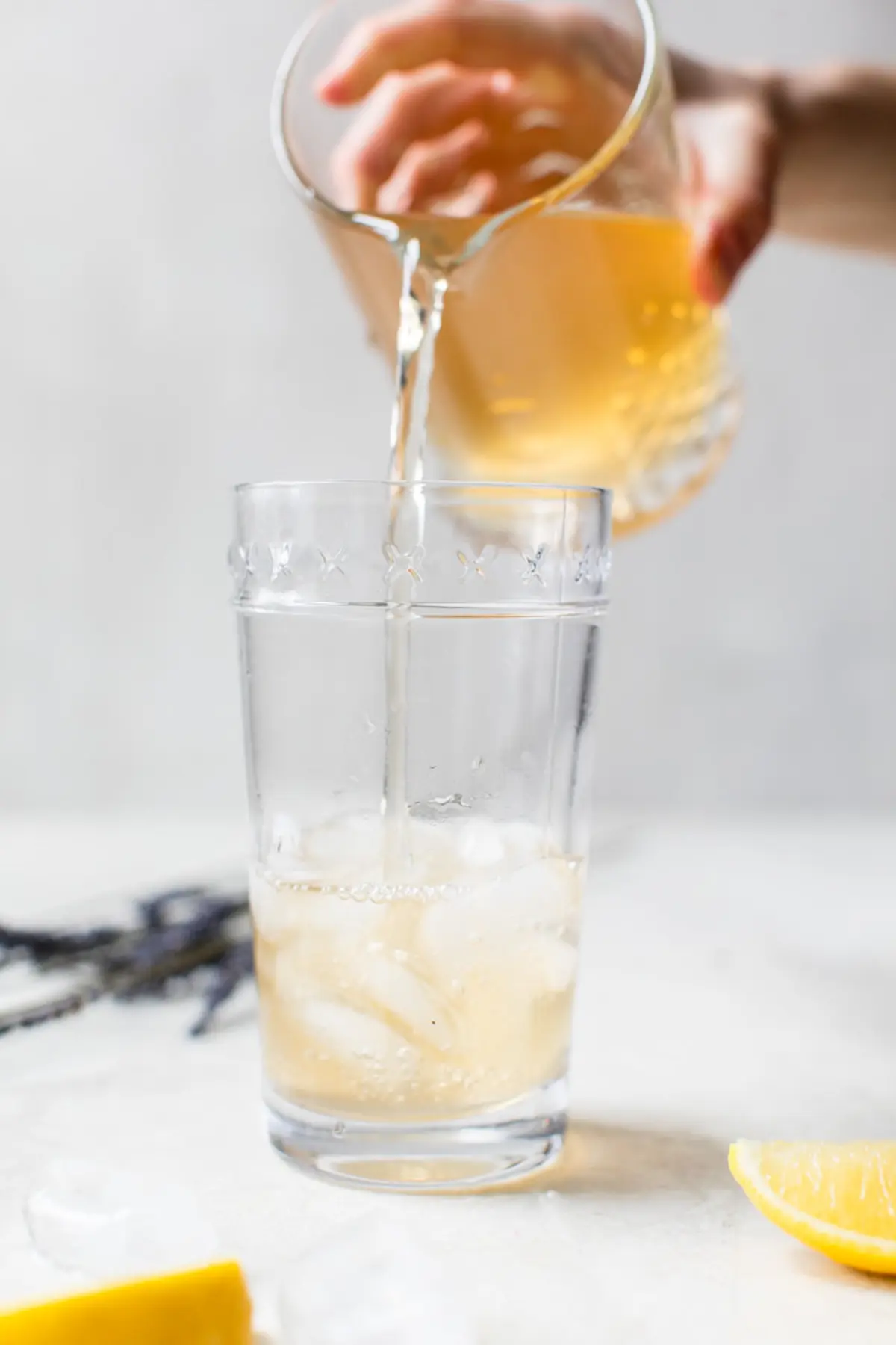 cocktail being poured into a glass filled with ice