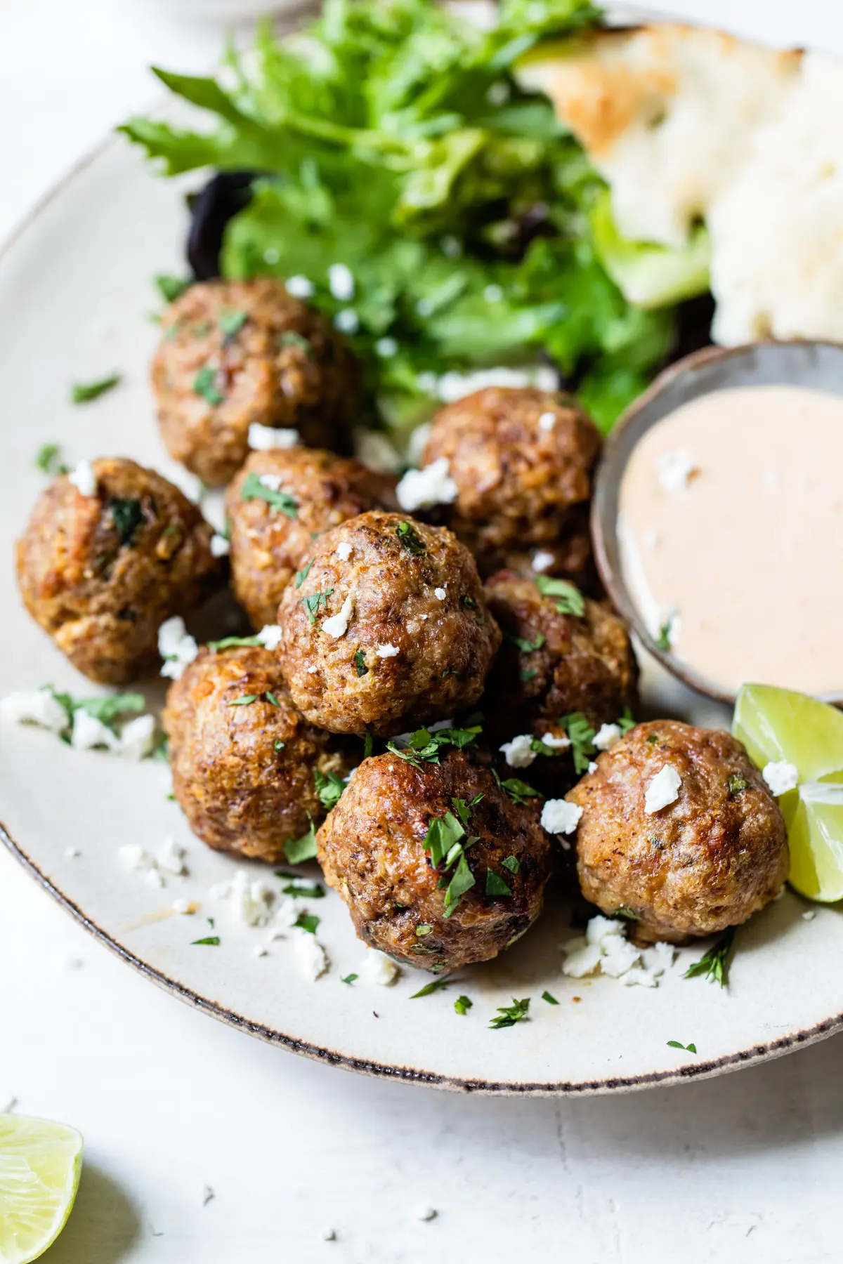 meatballs on a plate with side salad and sauce