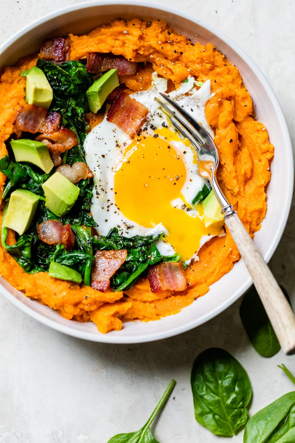 mashed sweet potatoes topped with spinach, bacon and a fried egg