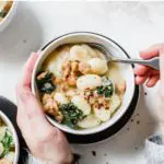 a bowl of soup with gnocchi, sausage and kale