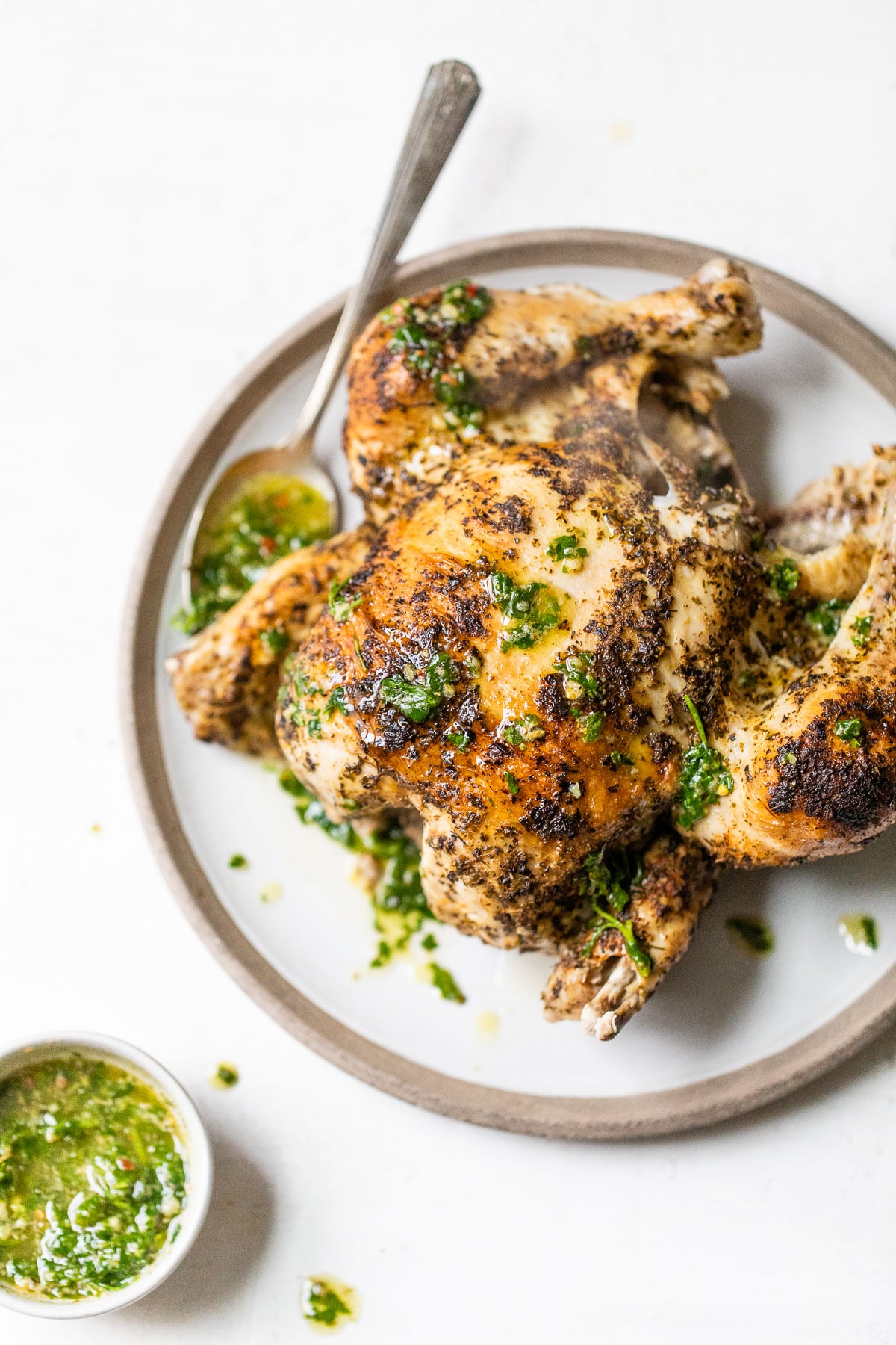 cooked rotisserie chicken on a plate drizzled with chimichurri sauce