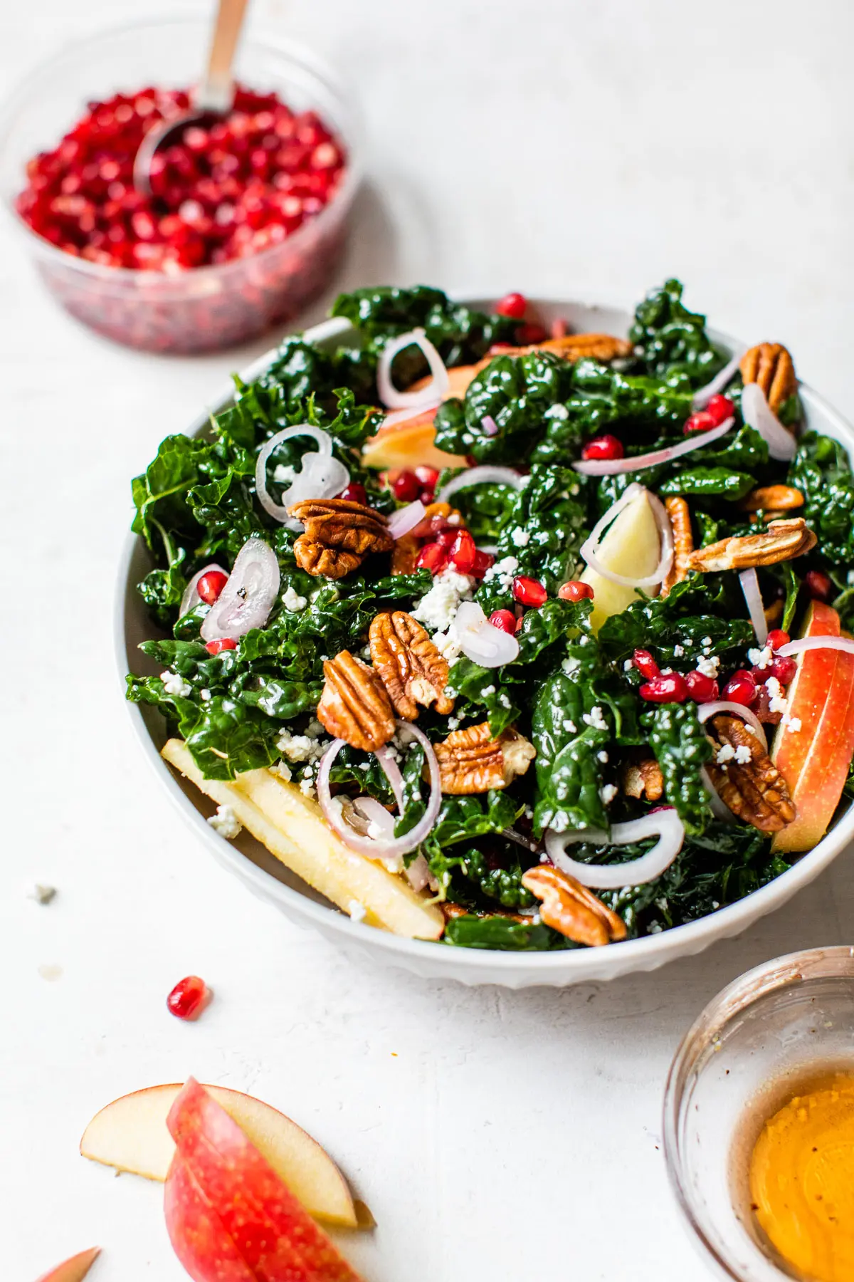 kale in a bowl with apple, pecans and pomegranate seeds
