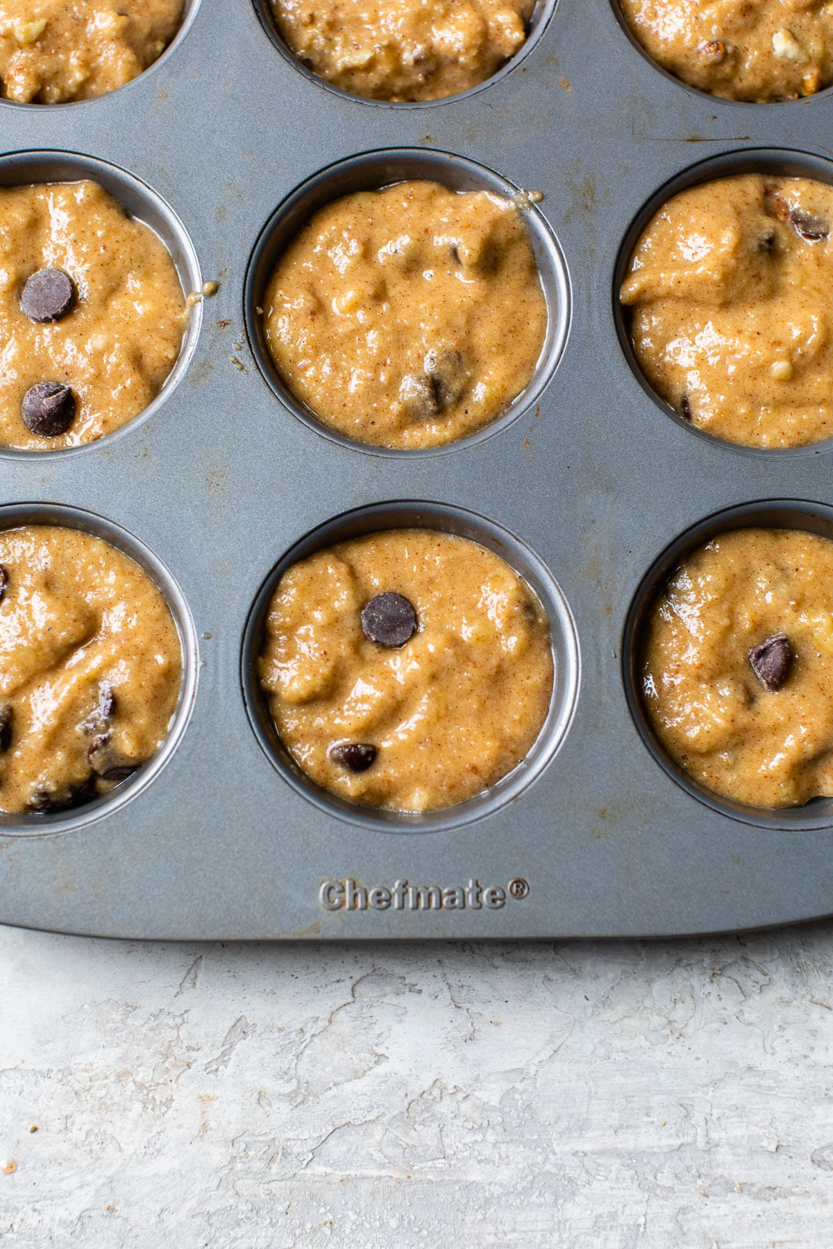 muffin batter with chocolate chips in a muffin tin