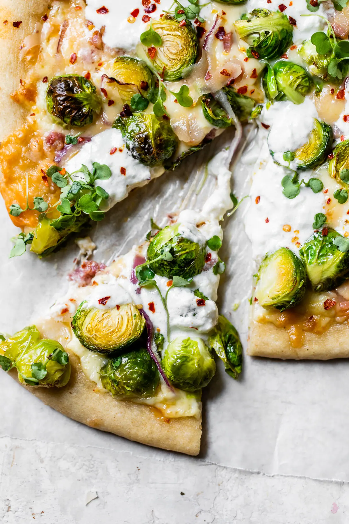 a slice of pizza topped with brussels sprouts and cheese