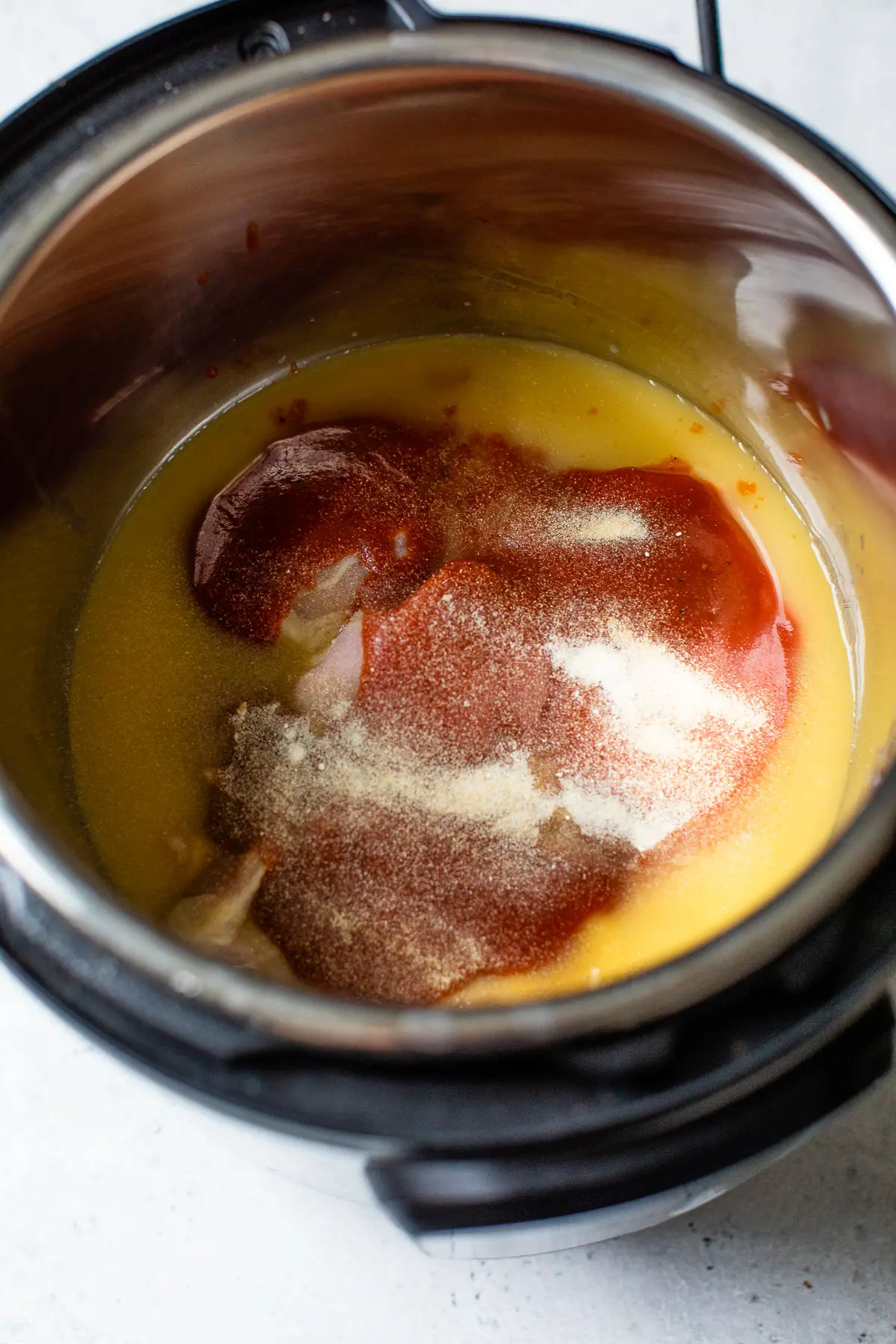 chicken, chicken broth, bbq sauce, and spices in a pressure cooker