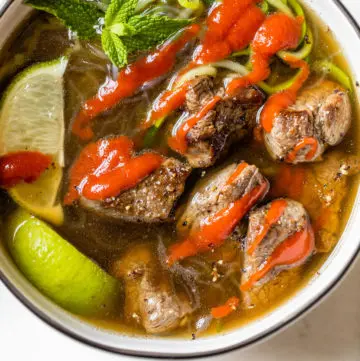 bowl of soup with beef topped with sriracha