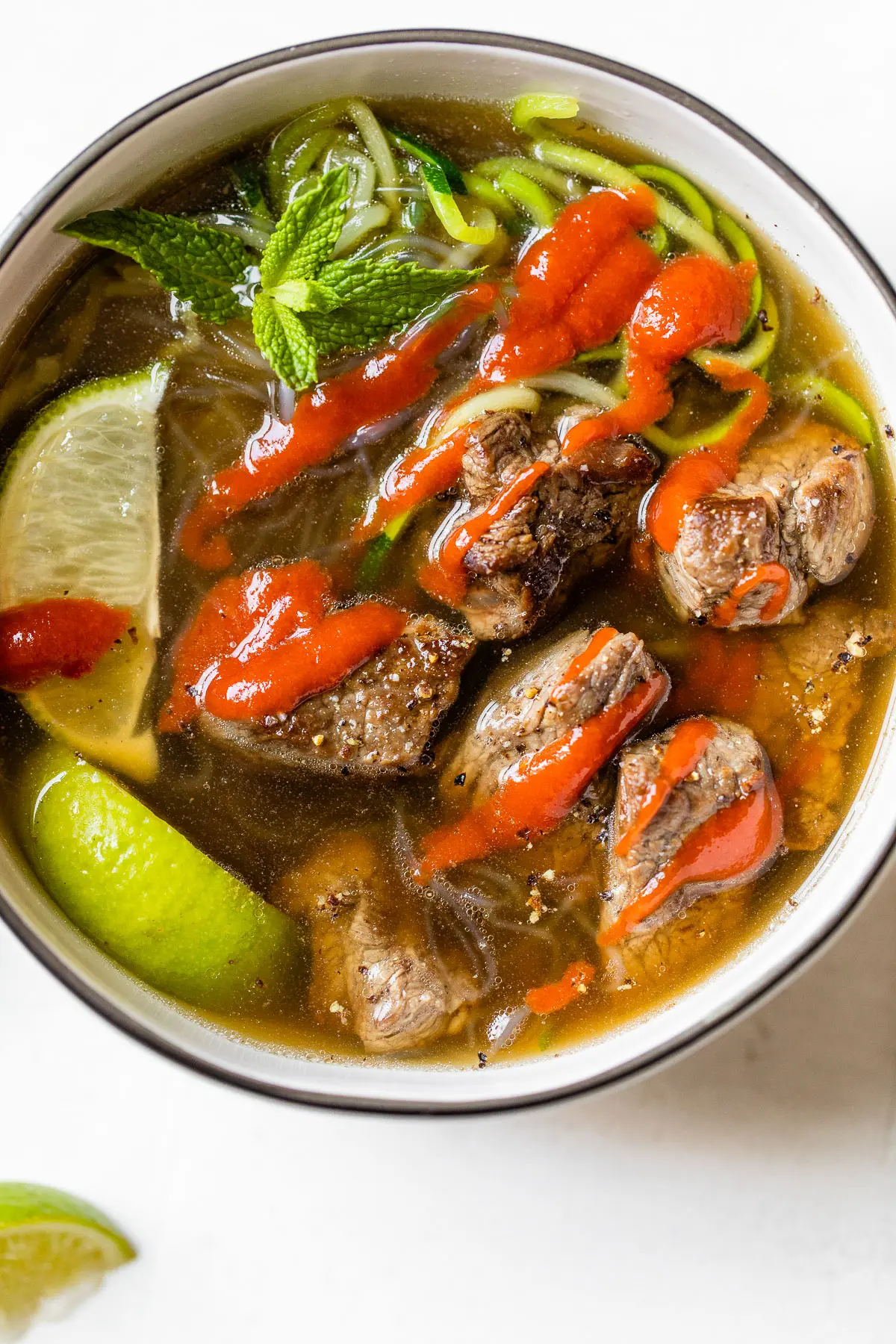 bowl of soup with beef topped with sriracha