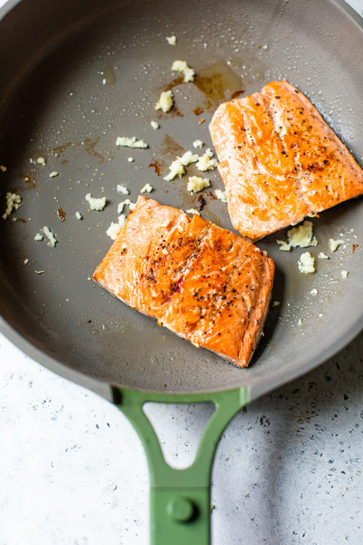 seared salmon in a skillet with garlic