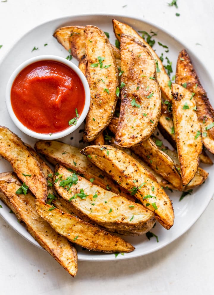 cooked potato wedges on a plate with a side of ketchup