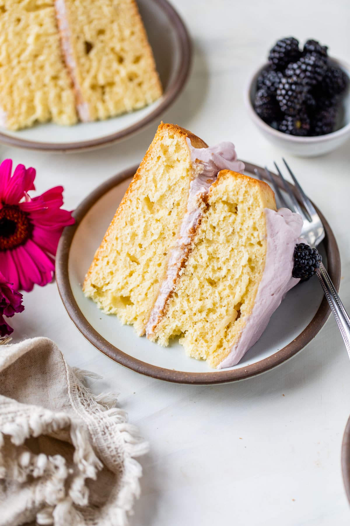a slice of yellow cake on a plate topped with purple icing