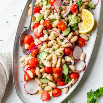 white beans, tomatoes, cucumbers on an oval-shaped platter
