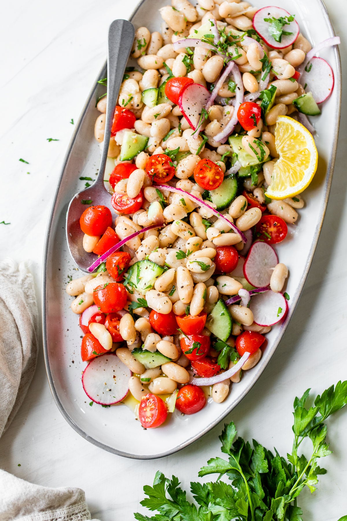 white beans, tomatoes, cucumbers on an oval-shaped platter