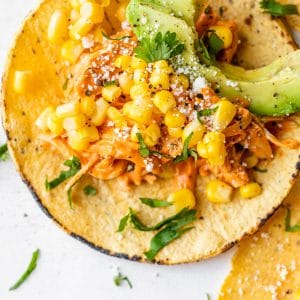 close up photo of a corn tortilla topped with chicken, corn and avocado