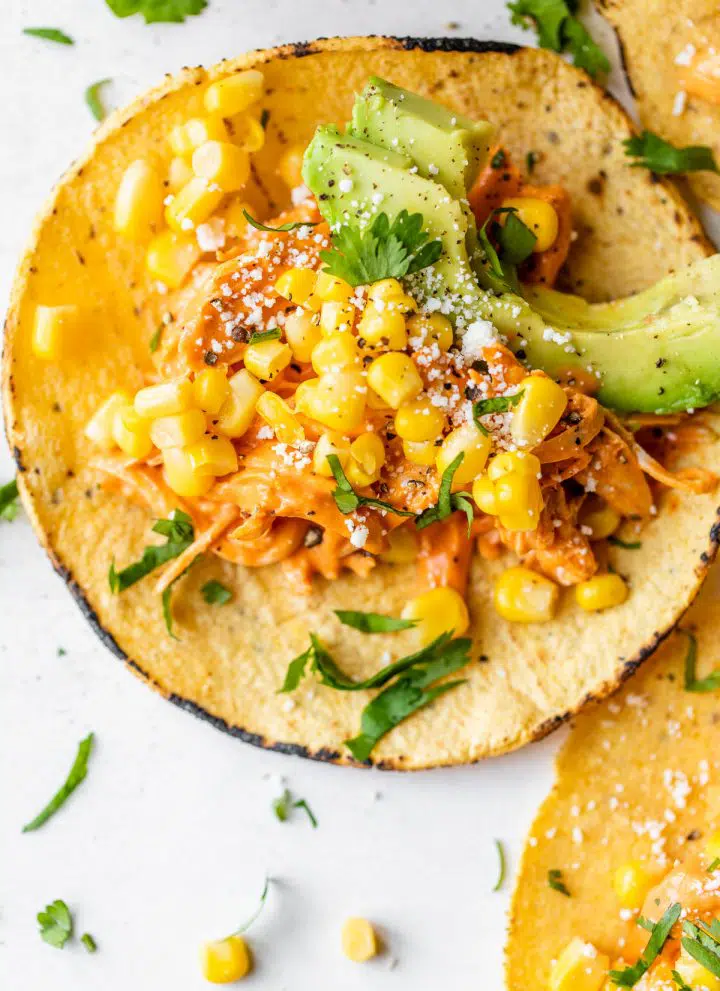 close up photo of a corn tortilla topped with chicken, corn and avocado
