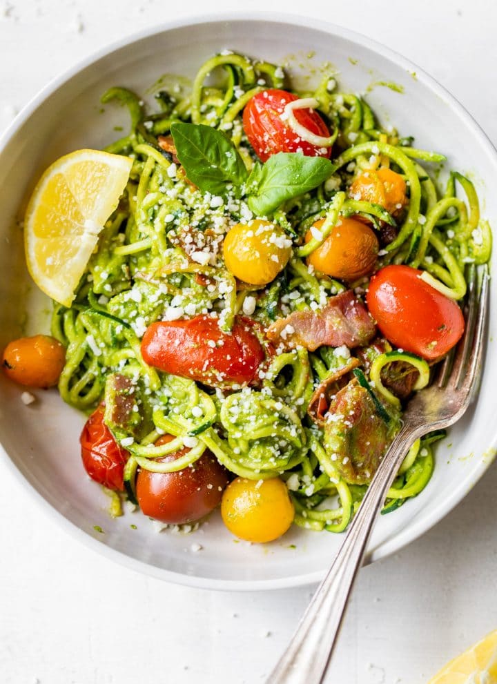 zucchini noodles in a bowl with tomatoes and bacon