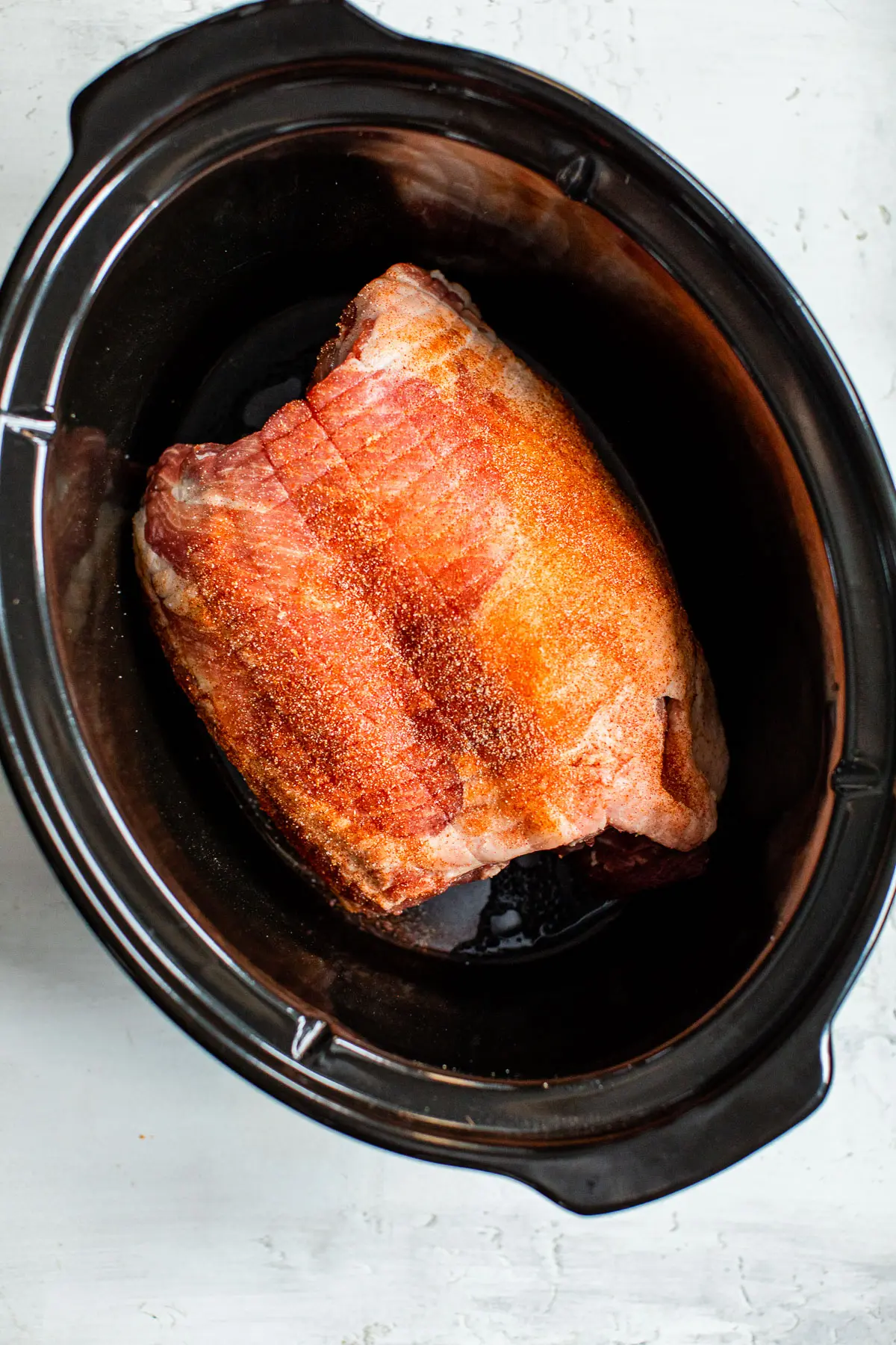 uncooked seasoned pork butt in a slow cooker