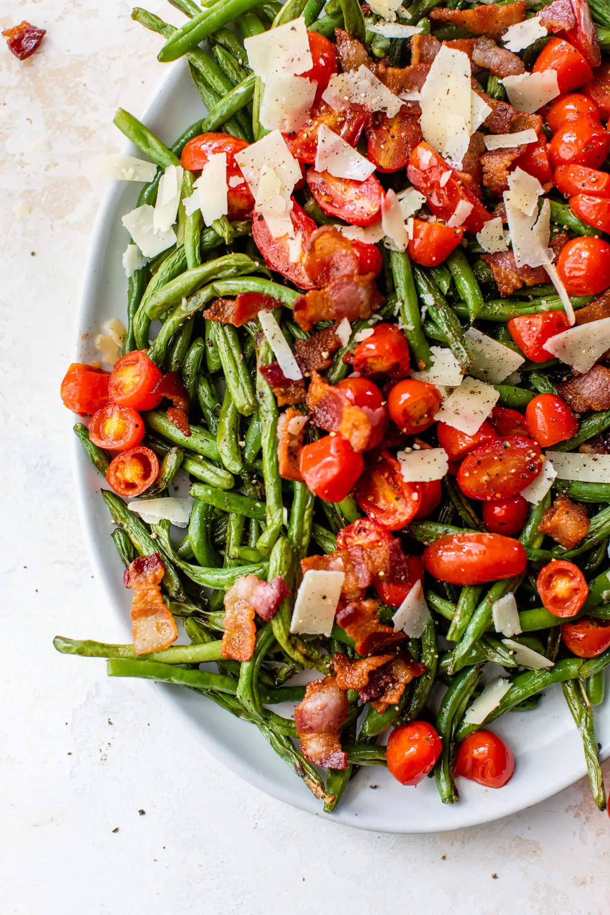 green beans, tomatoes, bacon, and shaved parmesan on an oval platter