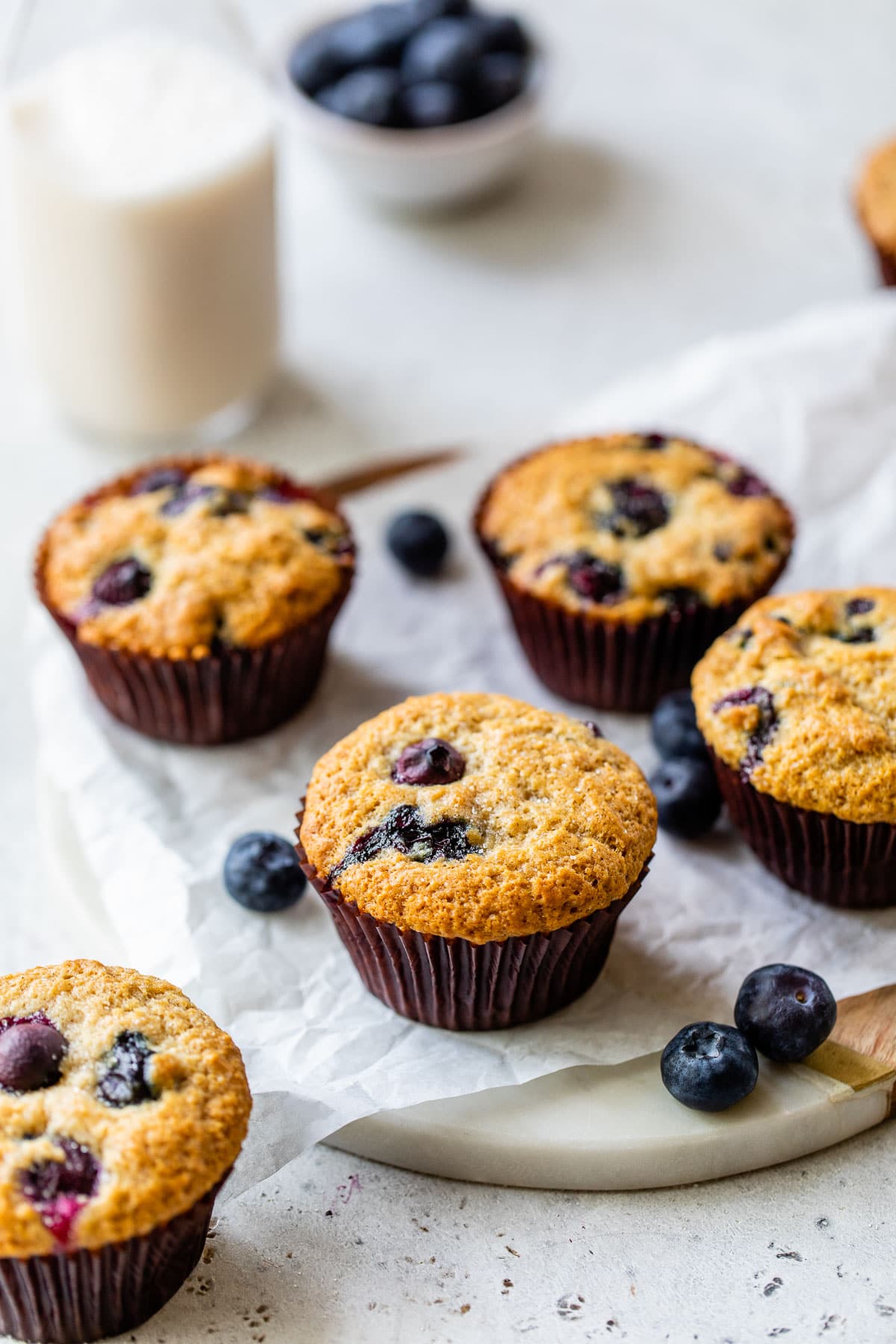 blueberry muffins and a glass of milk on parchment paper