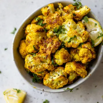 roasted cauliflower in a small bowl topped with chopped parsley