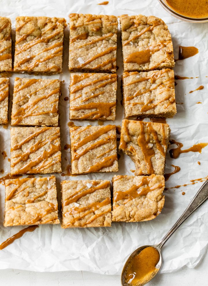 blondies on parchment paper with a caramel-colored drizzle over top