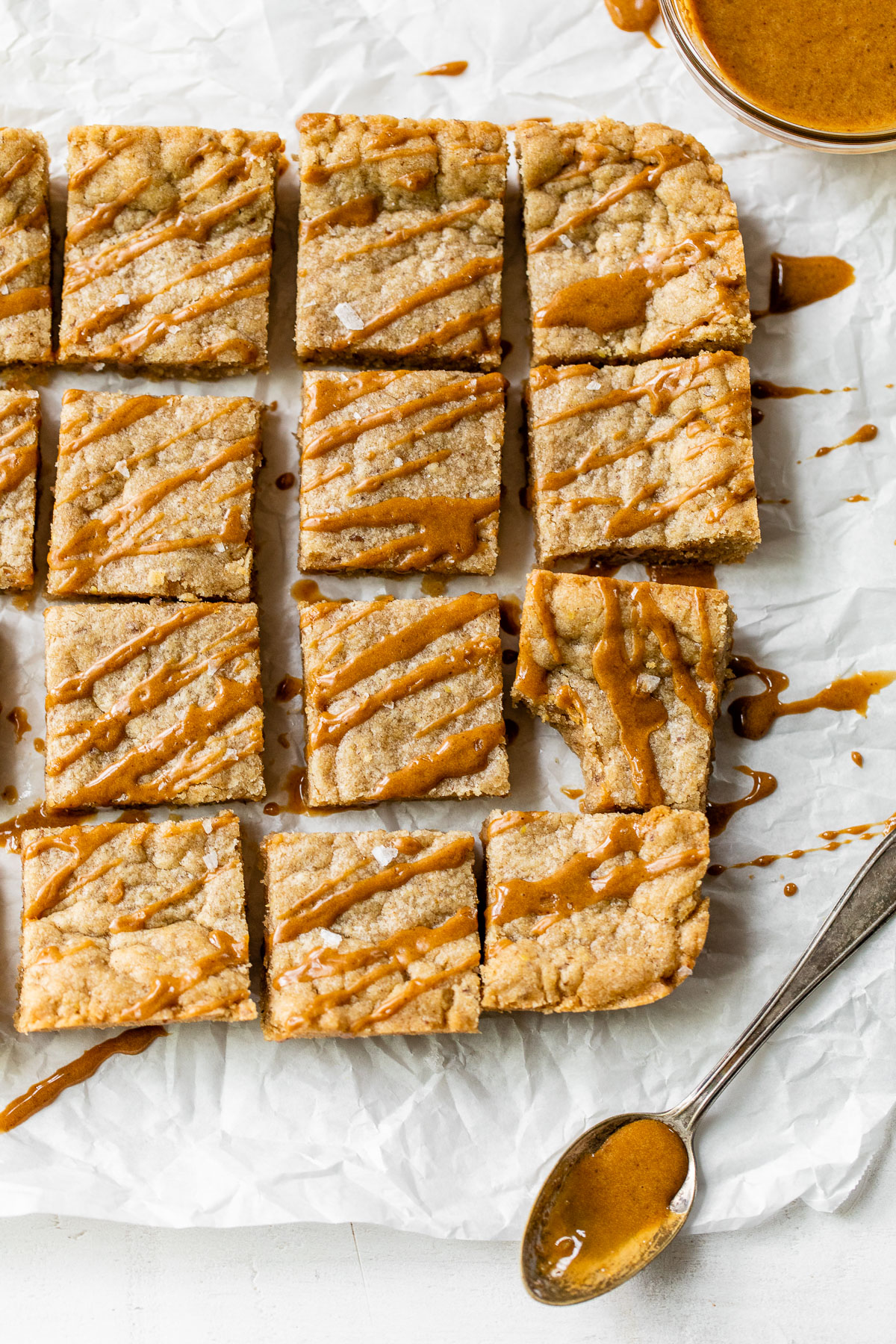 blondies on parchment paper with a caramel-colored drizzle over top