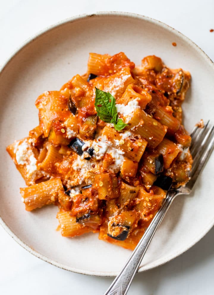 bowl with pasta, eggplant, ricotta, and fresh basil all covered in marinara sauce
