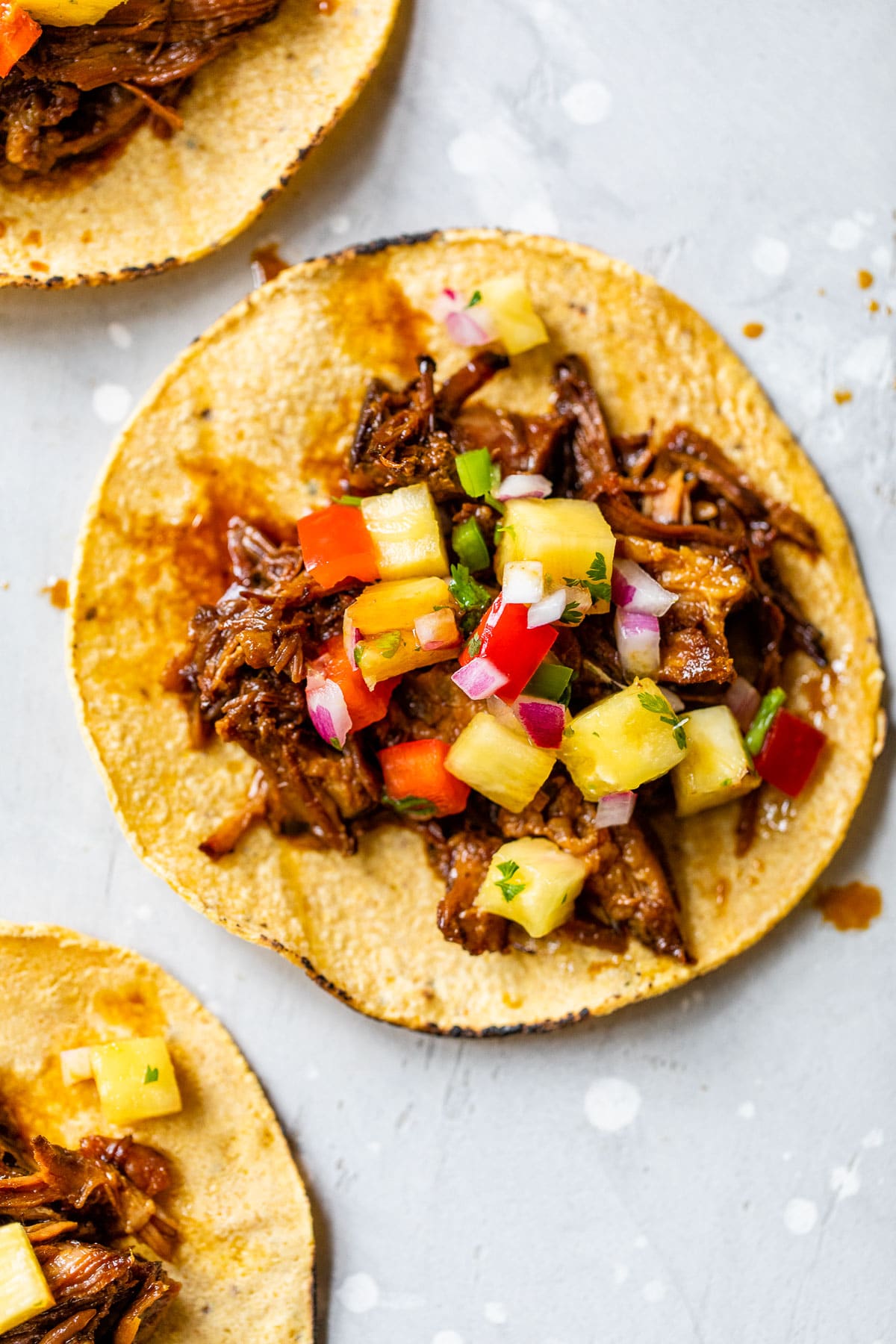 corn taco shell topped with shredded pork and pineapple salsa