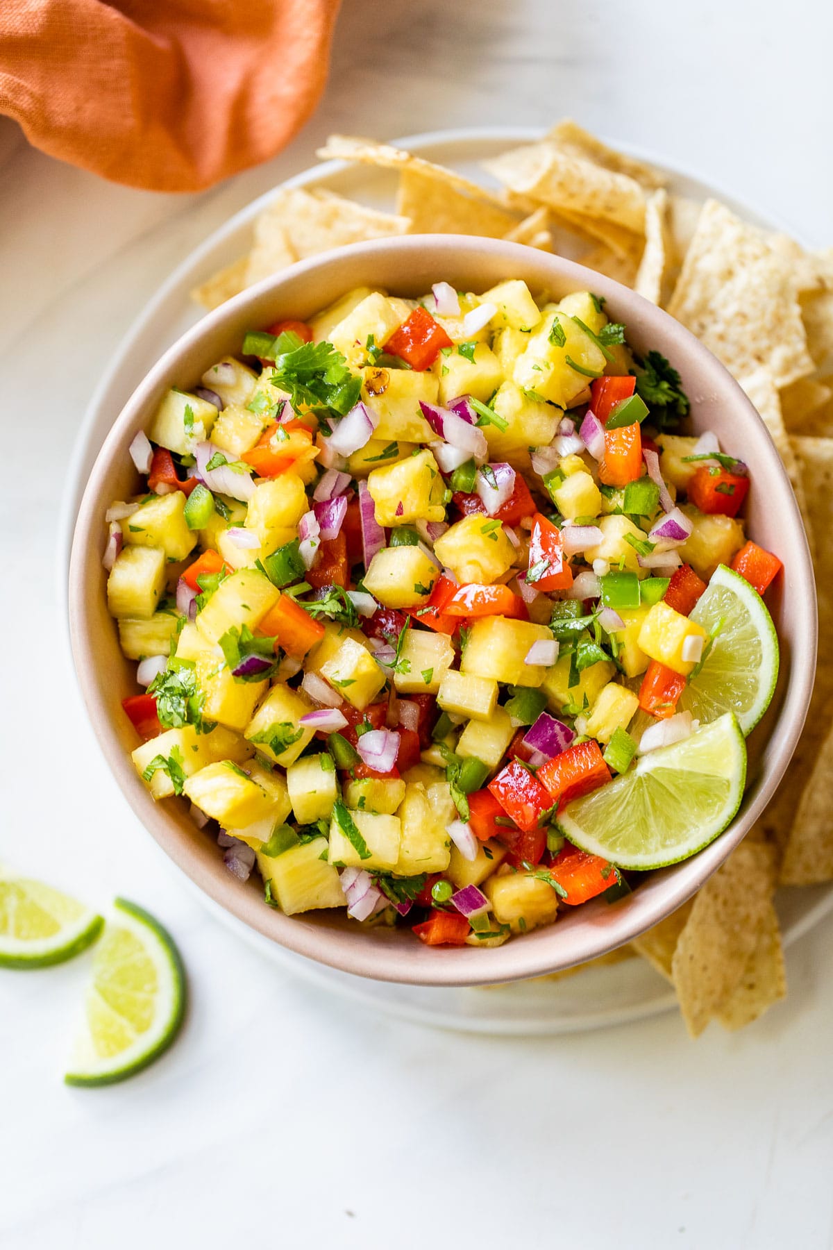 a small bowl of pineapple salsa beside a pile of tortilla chips