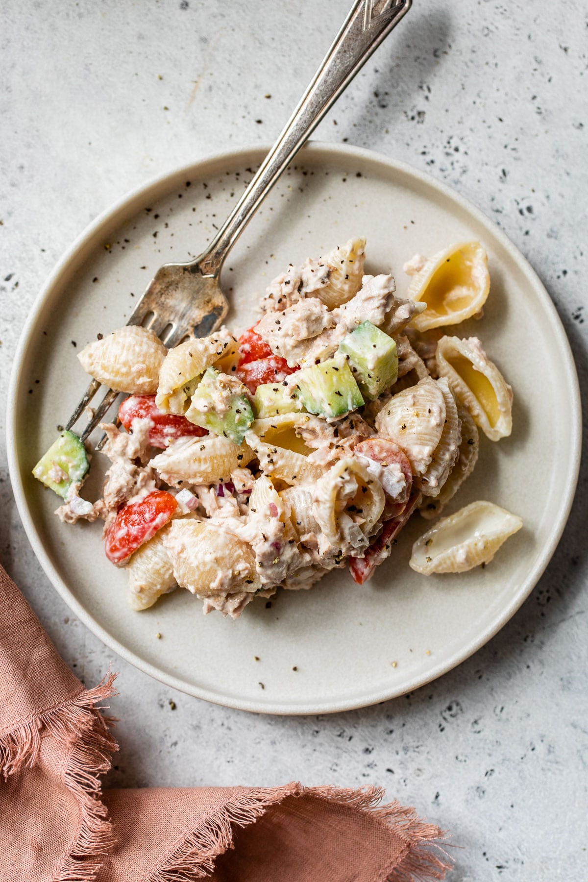 pasta salad on a small plate beside a pink linen