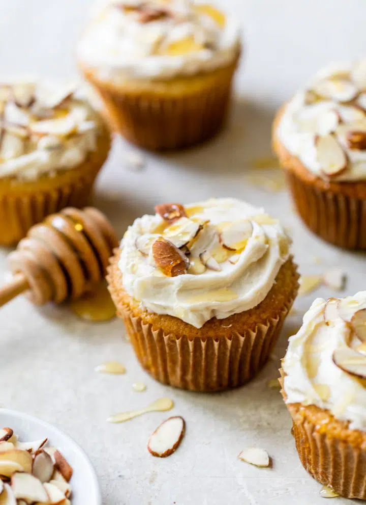 several almond cupcakes on a table topped with sliced almonds