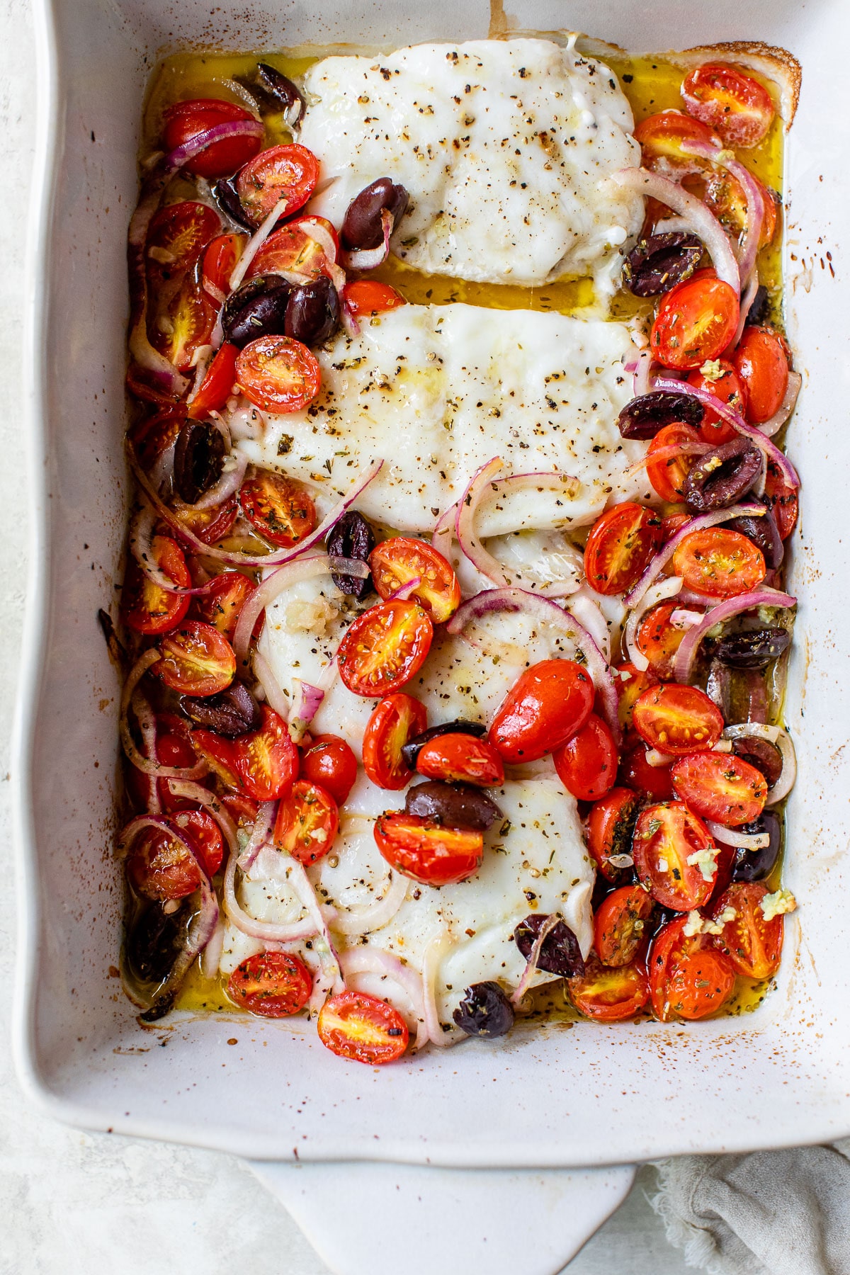 four baked cod fillets in a baking dish