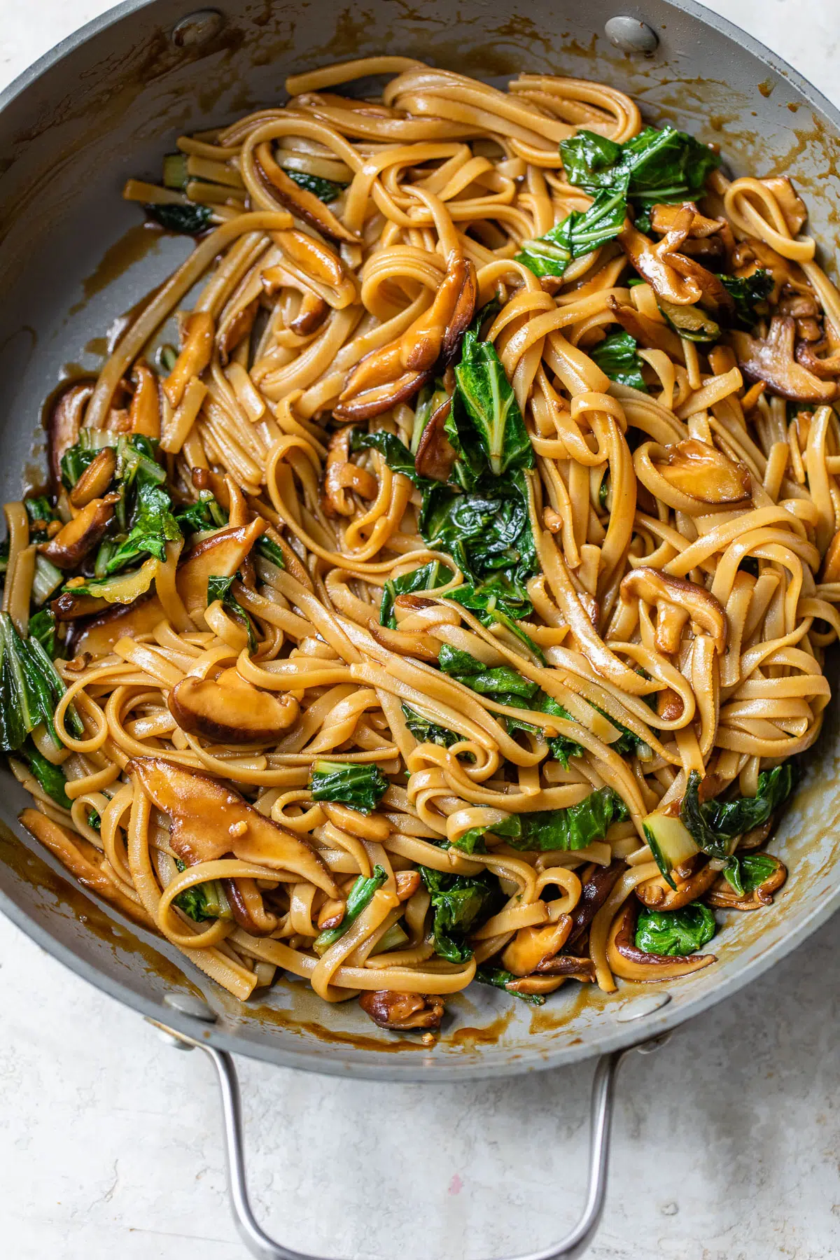 skillet with long noodles, mushrooms and bok choy