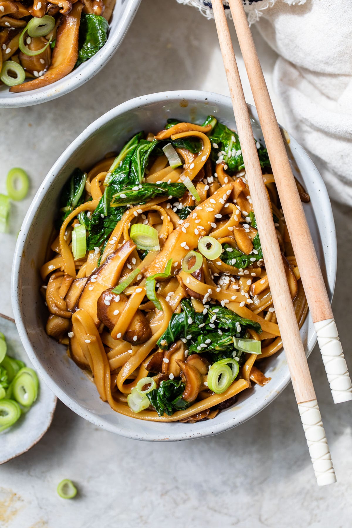 a bowl of long noodles with cooked bok choy and scallions