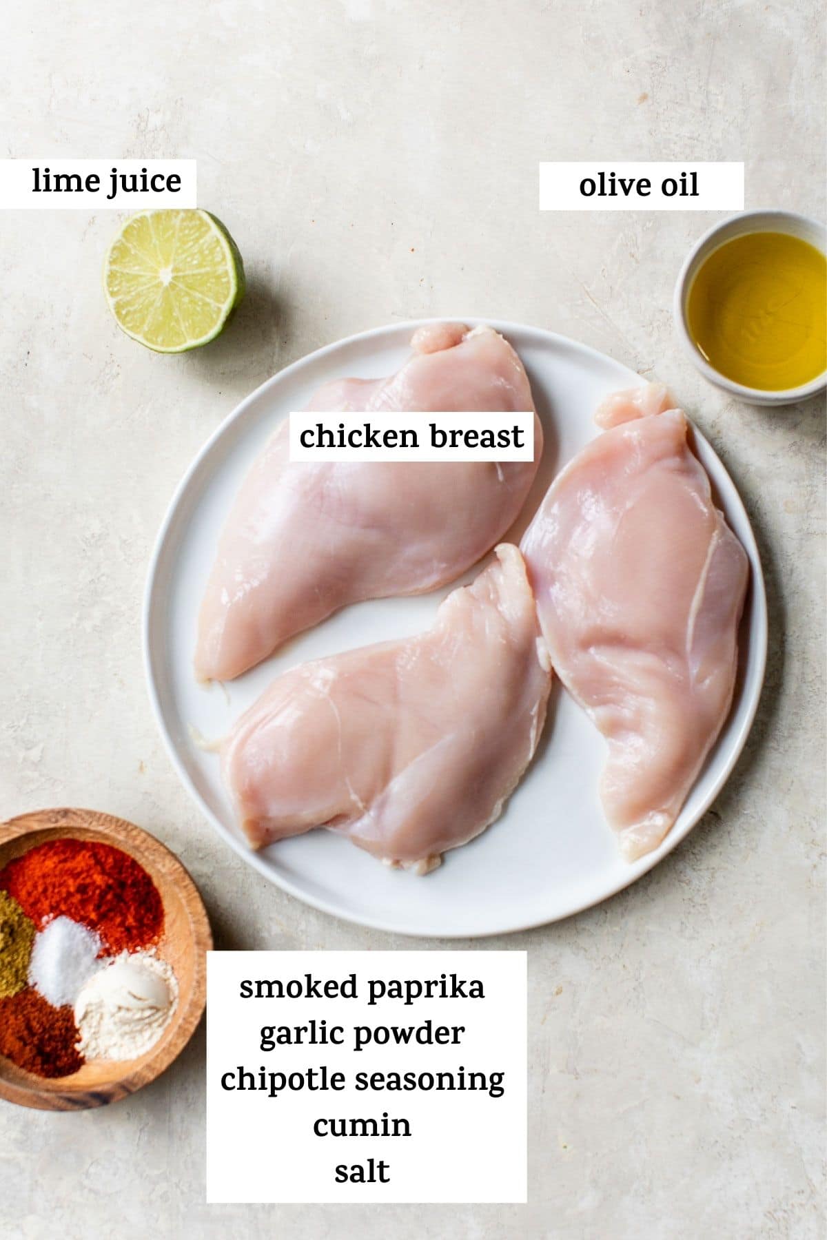 raw chicken breasts on a plate, along with olive oil, lime juice and spices