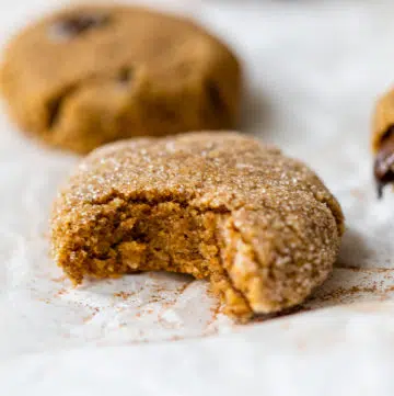 pumpkin cookie on parchment paper with a bite taken out of it
