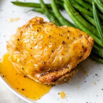 chicken thigh on a plate with gravy and green beans