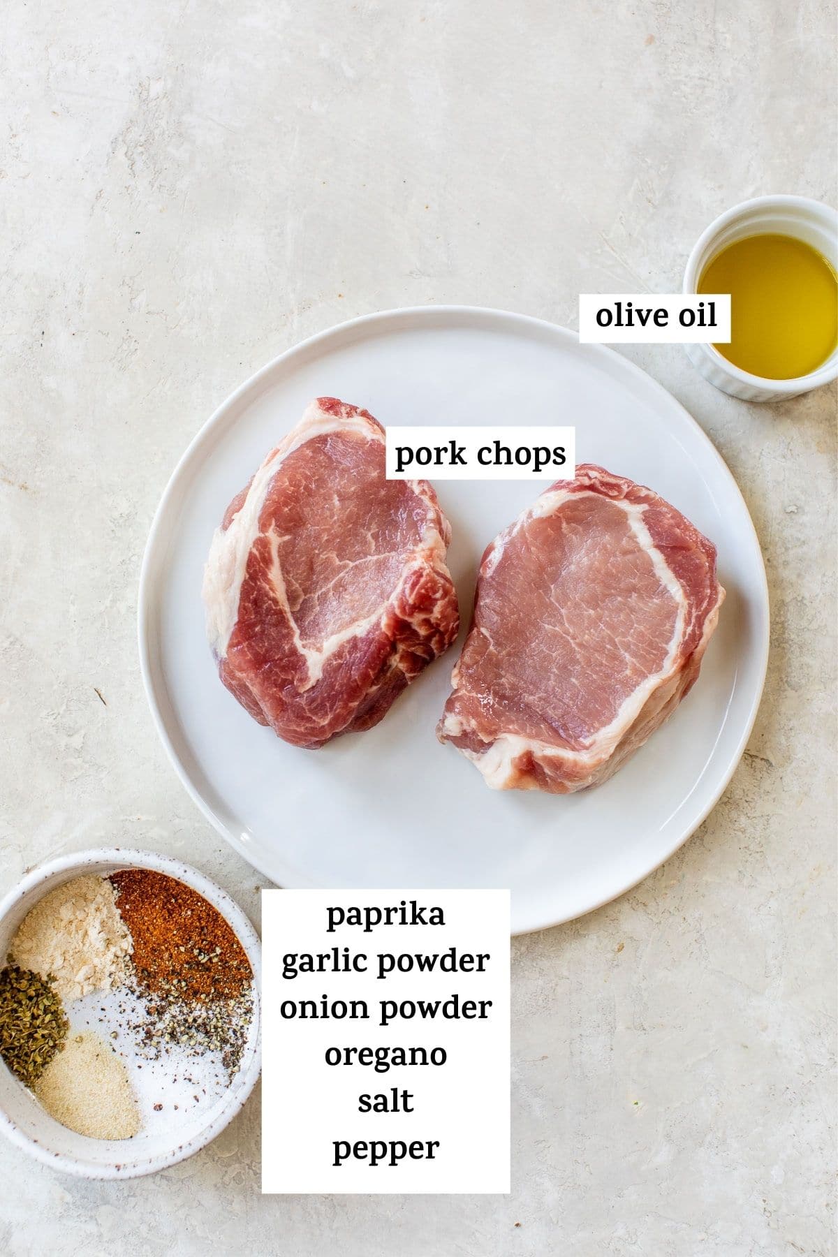 raw pork chops on a plate beside a bowl of spices
