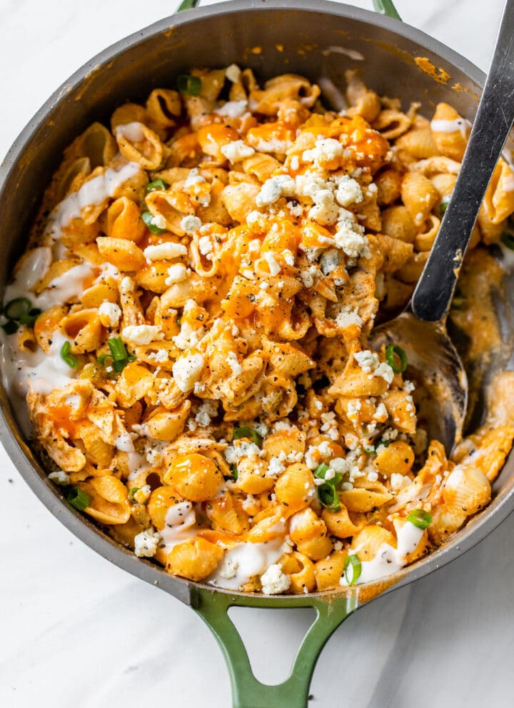a skillet filled with pasta, chicken and buffalo sauce