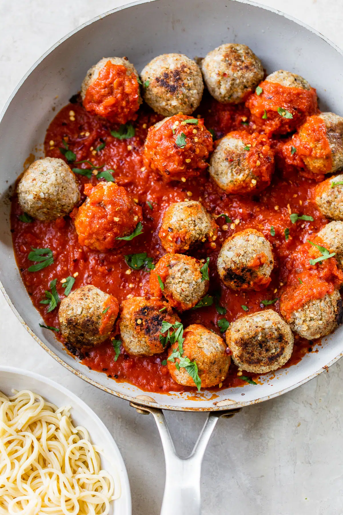 skillet filled with meatballs coated in marinara sauce