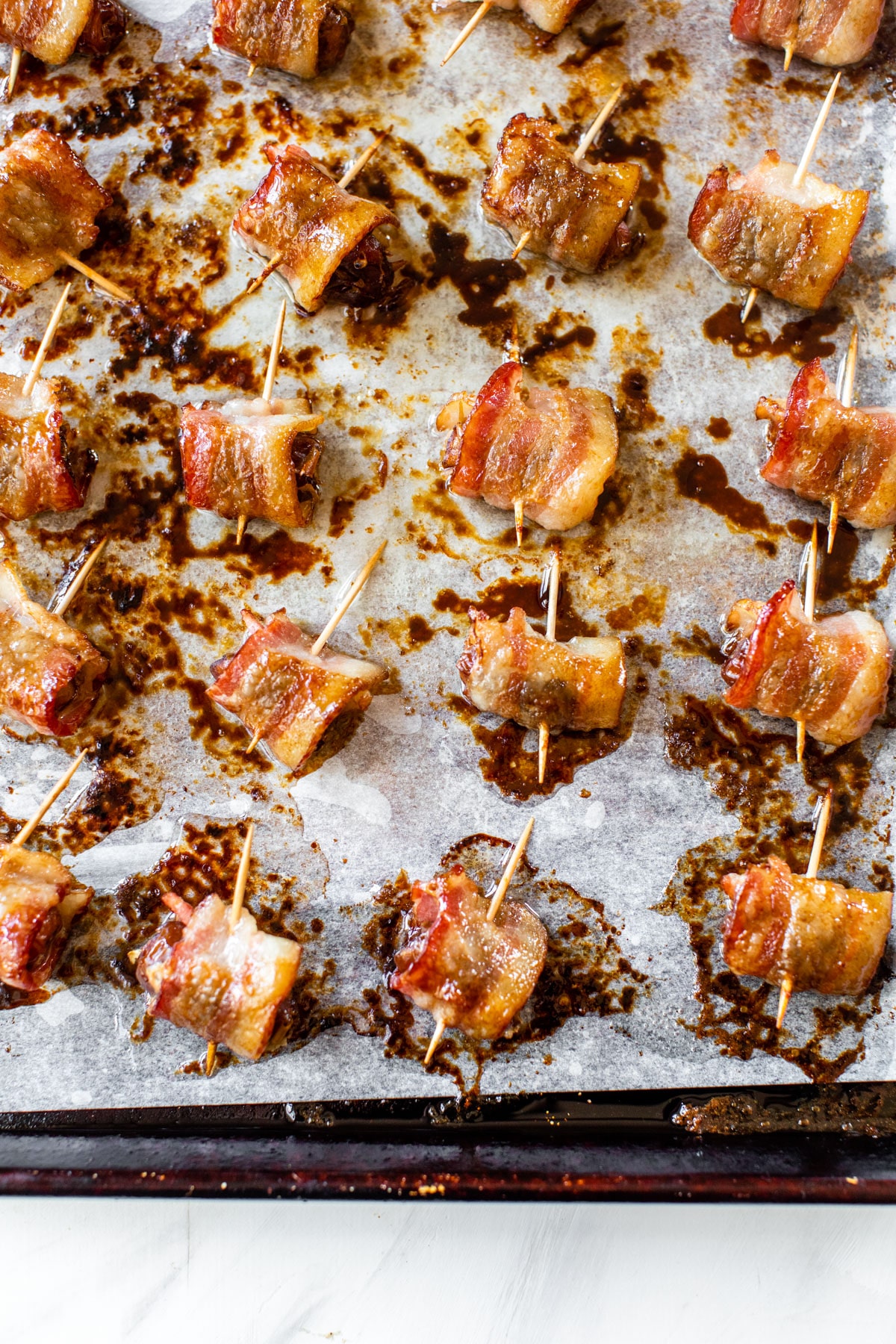 bacon-wrapped dates on a baking sheet with parchment paper