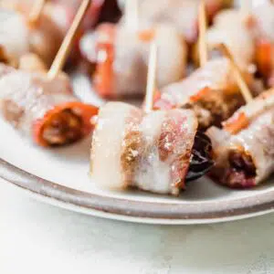 bacon-wrapped dates with toothpicks on a plate