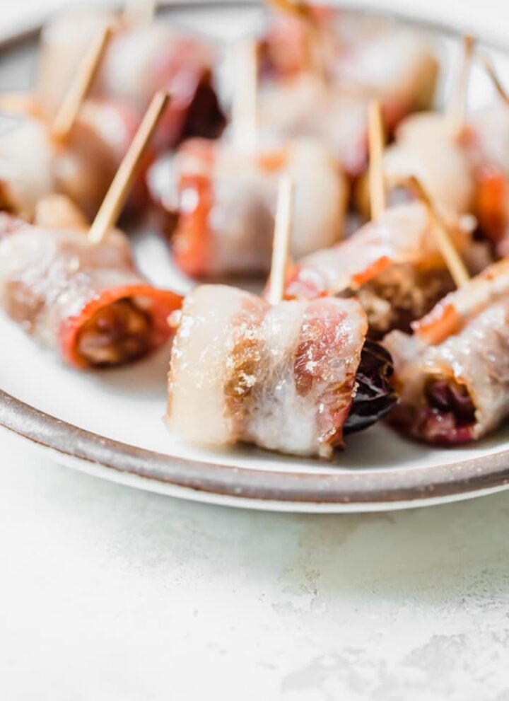 bacon-wrapped dates with toothpicks on a plate
